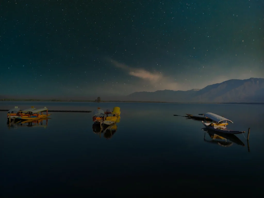 boats standing on a lake at night full of stars